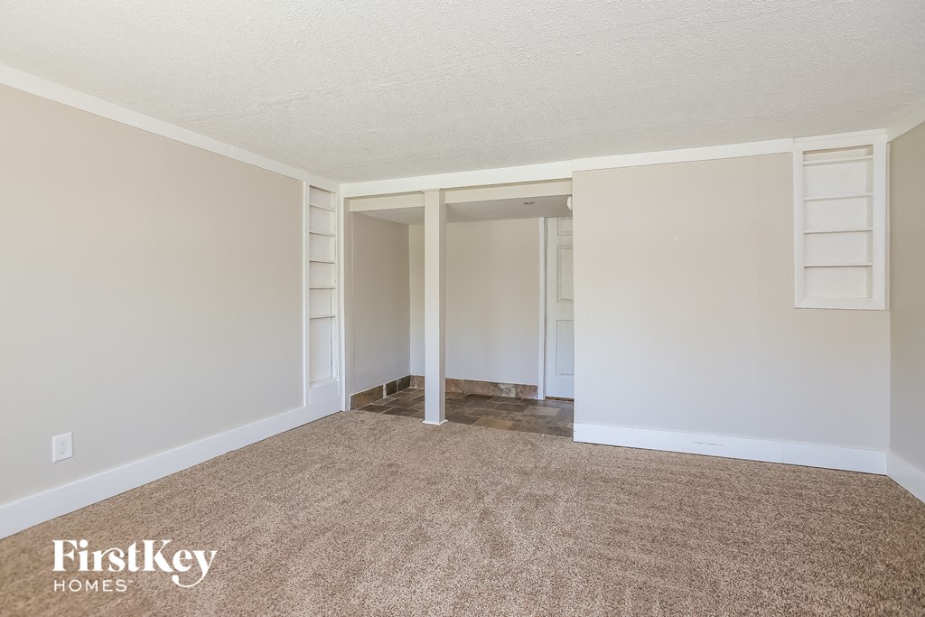 a living room with a carpeted floor and a doorway to a closet