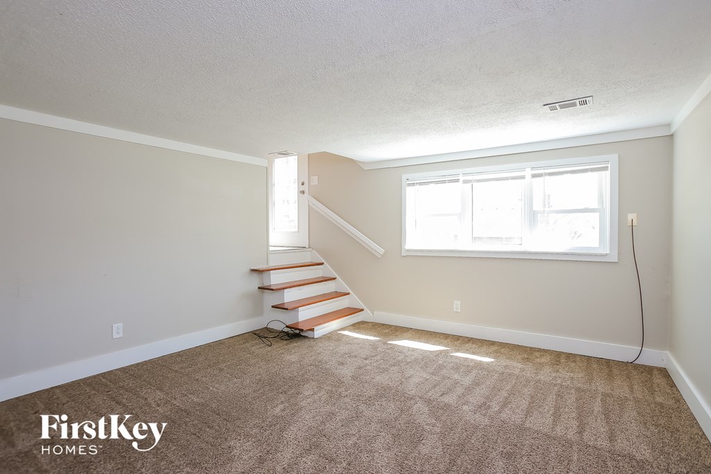 a living room with carpeted stairs and a window