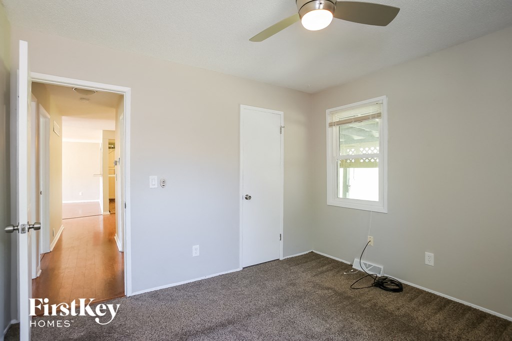 an empty living room with carpet and a ceiling fan