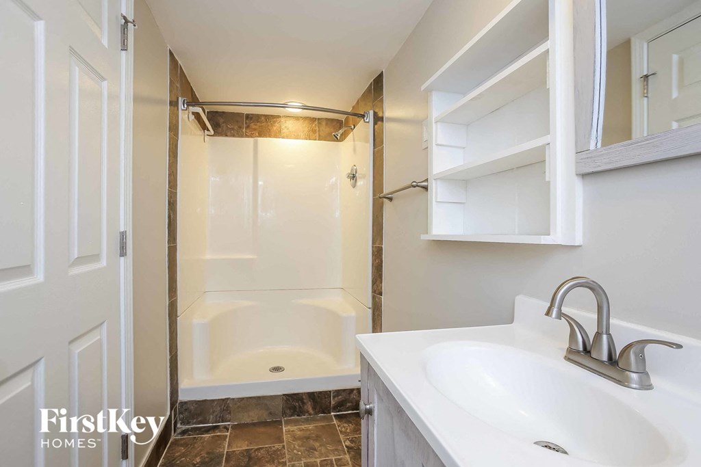 a white bathroom with a shower and a sink