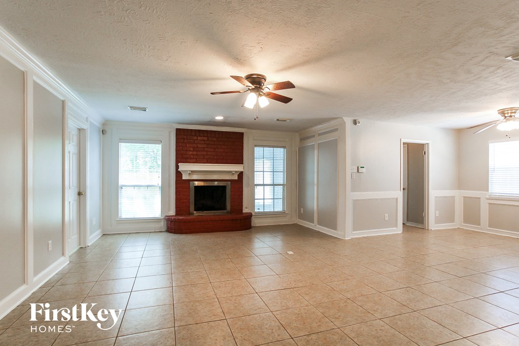 an empty living room with a fireplace and a ceiling fan
