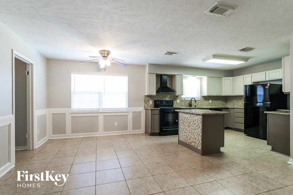 a kitchen with black appliances and a ceiling fan
