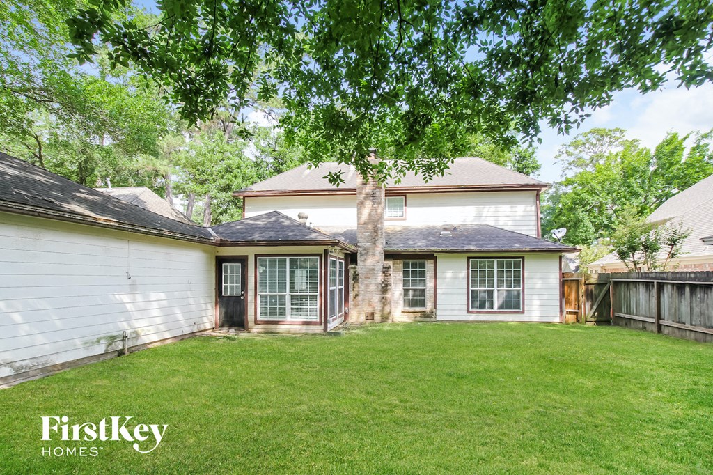a backyard with a white house and a tree