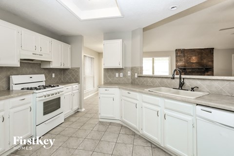A kitchen with white cabinets and a stove top oven.