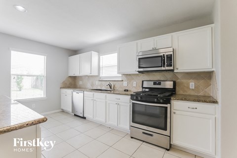 A kitchen with white cabinets and appliances.