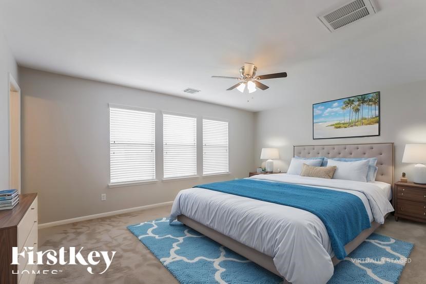 A bedroom with a large bed and a ceiling fan.