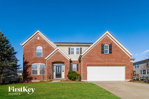 a red brick house with a white garage door and a green lawn