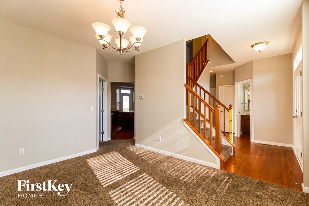 the entryway of a house with a staircase and a carpeted floor
