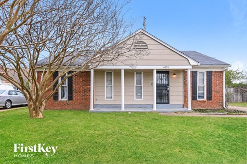 a small brick house with a tree in front of it