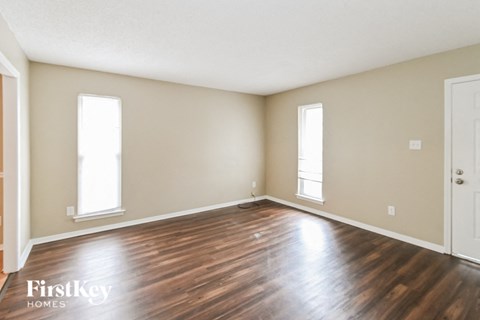 the living room of an empty house with wood floors and a door