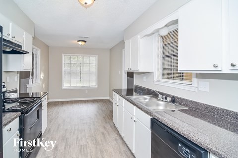 A kitchen with white cabinets and a black dishwasher.