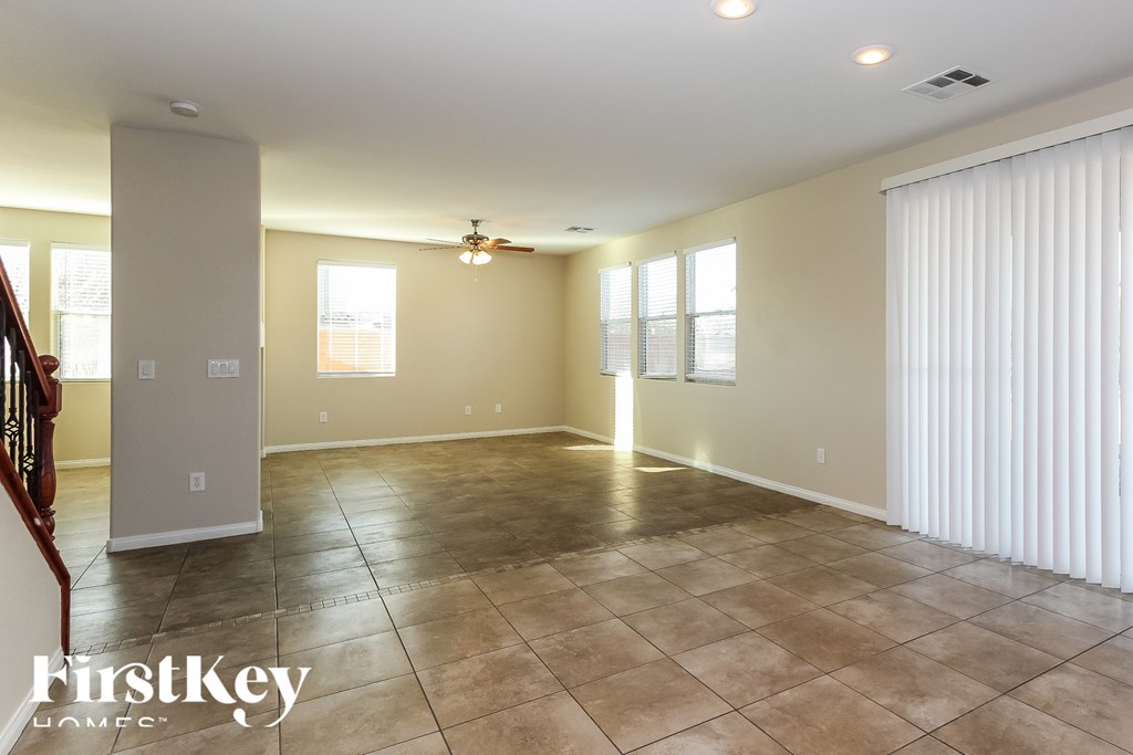 A spacious room with tile flooring and a ceiling fan.