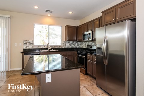 A kitchen with a stainless steel refrigerator and a black countertop.