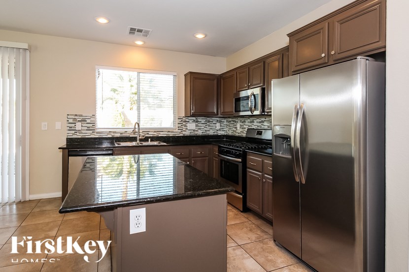 A kitchen with a black counter top and stainless steel appliances.