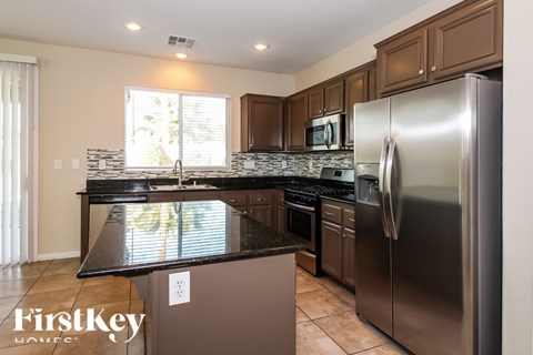A kitchen with a black counter top and stainless steel appliances.