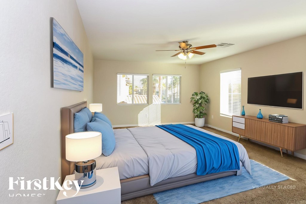 A bedroom with a bed, a ceiling fan, and a painting on the wall.