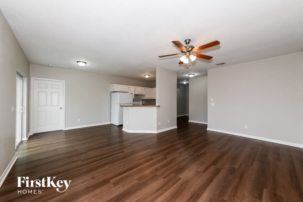 A spacious room with a ceiling fan and wooden flooring.