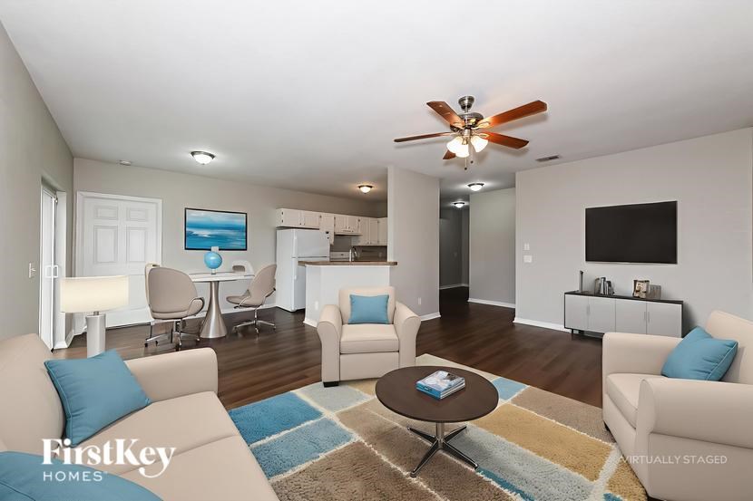 A living room with a beige couch, a coffee table, and a ceiling fan.