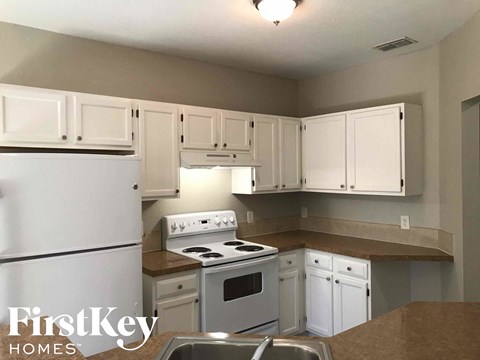 A kitchen with white cabinets and a stove top oven.