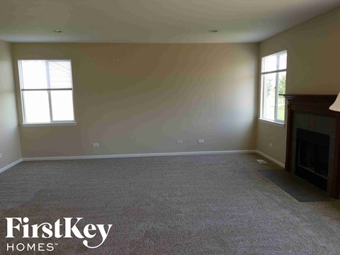 A spacious living room with a fireplace and two windows.
