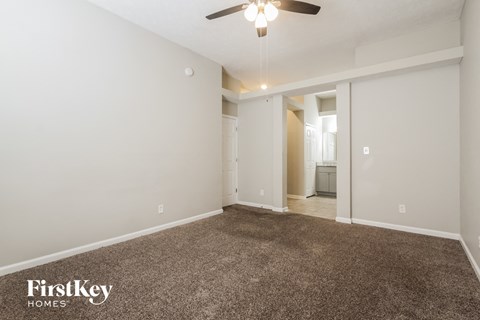a spacious living room with carpet and a ceiling fan