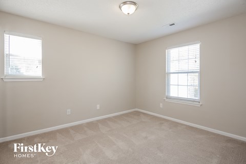 a bedroom with a carpeted floor and two windows