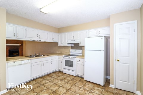 a kitchen with white cabinets and appliances and a white refrigerator