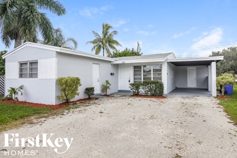 a white house with a driveway and palm trees