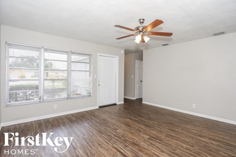 an empty living room with a ceiling fan and a window