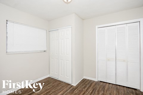 a bedroom with two closets and a window and wood flooring
