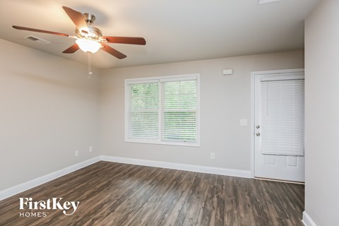 the spacious living room with a ceiling fan and wood flooring