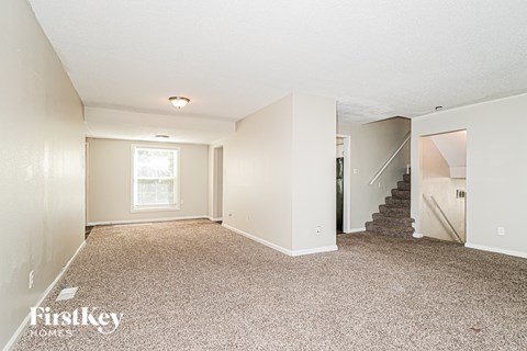 A spacious room with a staircase leading to another room.