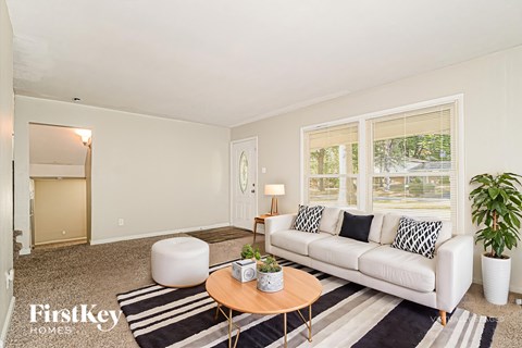 A living room with a white couch, a coffee table, and a rug.