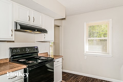 A kitchen with a black stove top oven and white cabinets.