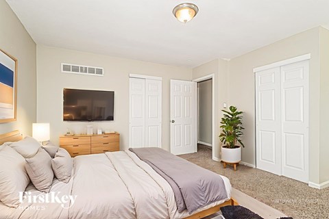 A bedroom with a large bed and a flat screen TV mounted on the wall.