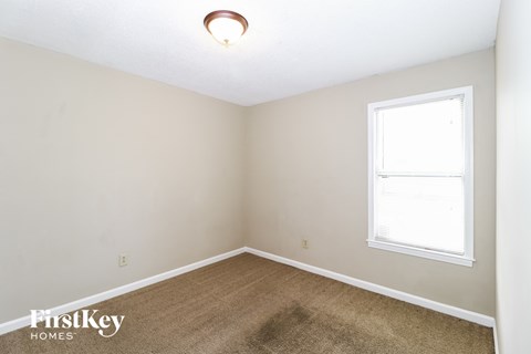 a bedroom with a carpet and a window