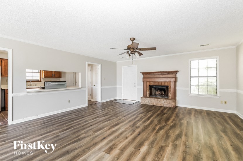 an empty living room with a fireplace and a ceiling fan