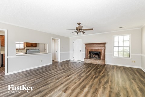 an empty living room with a fireplace and a ceiling fan