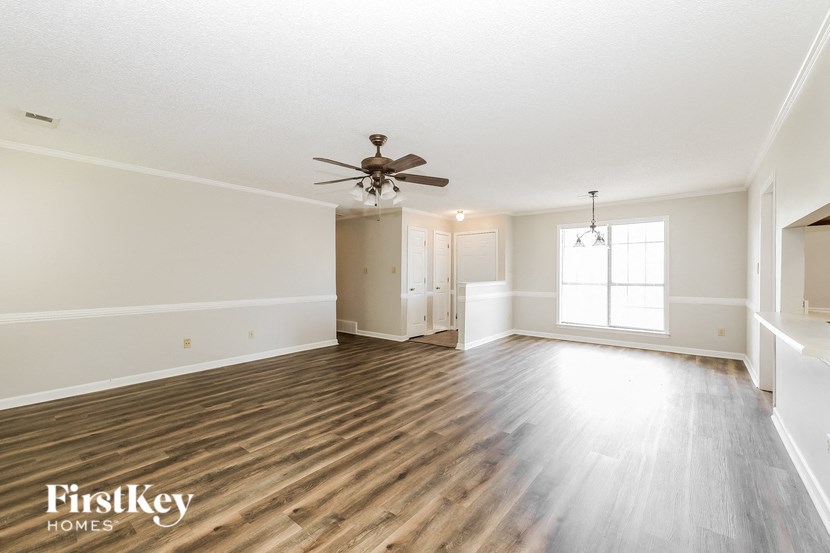 an empty living room with a ceiling fan and wood floors