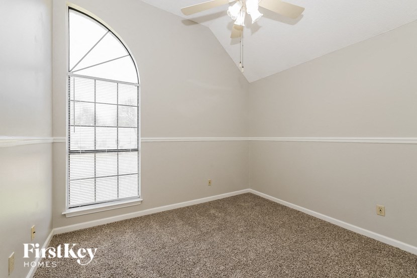 an empty room with a large window and a ceiling fan