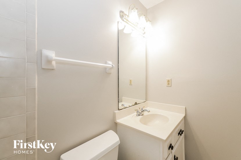 a white bathroom with a sink toilet and a mirror