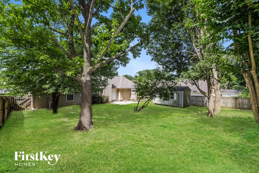 a yard with trees and a house in the background