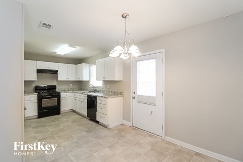 A kitchen with white cabinets and a black stove top oven.