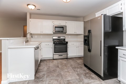 A kitchen with a black refrigerator and white cabinets.