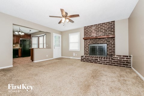 A spacious living room with a brick fireplace and a ceiling fan.