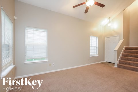 an empty living room with stairs and a ceiling fan