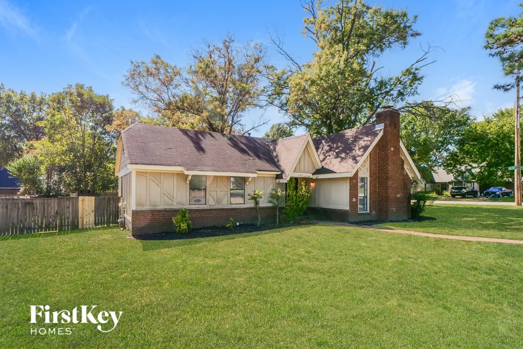 A house with a brown roof and a white garage door is surrounded by a grassy lawn.