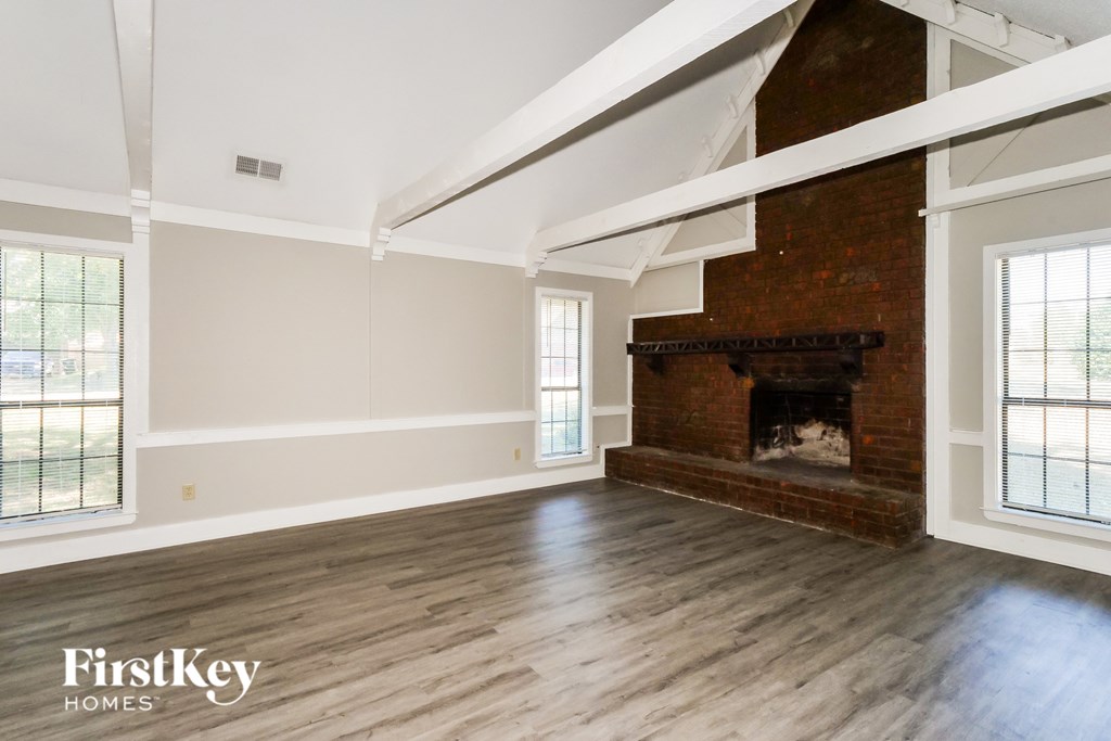 A large empty room with a fireplace and wooden floors.