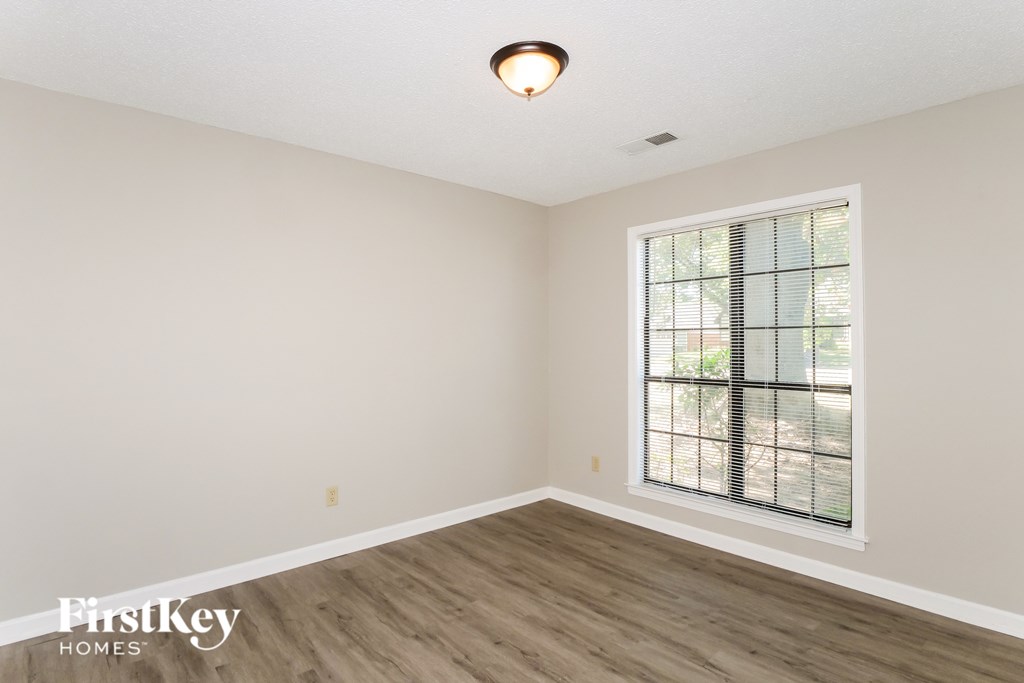 A room with a window and wooden flooring.