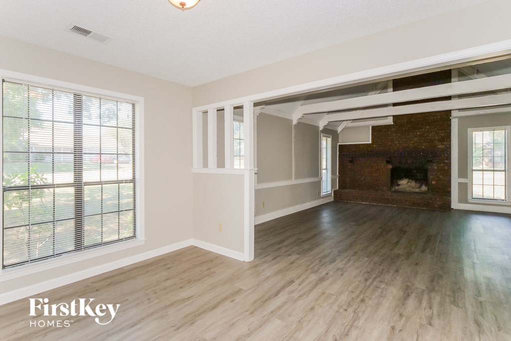 A spacious room with wooden flooring and a fireplace.